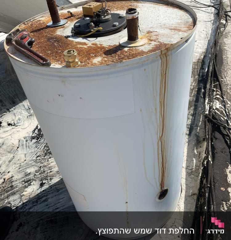 דוד שמש עם חלודה על הגג, צינורות וחיבורים גלויים